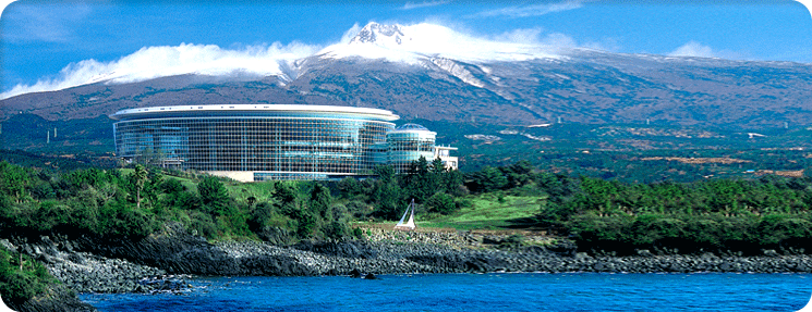 The ICC Jeju convention centre on the Jeju coastline with Hallasan rising behind it